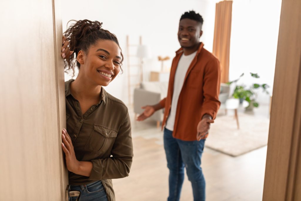 A young couple welcomes you into their apartment, happy to show off the benefits.